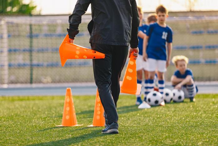 Football coach placing cones on ground